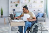 Jeune homme en fauteuil roulant qui utilise un ordinateur sur un bureau